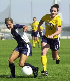 Two soccer players running towards the ball